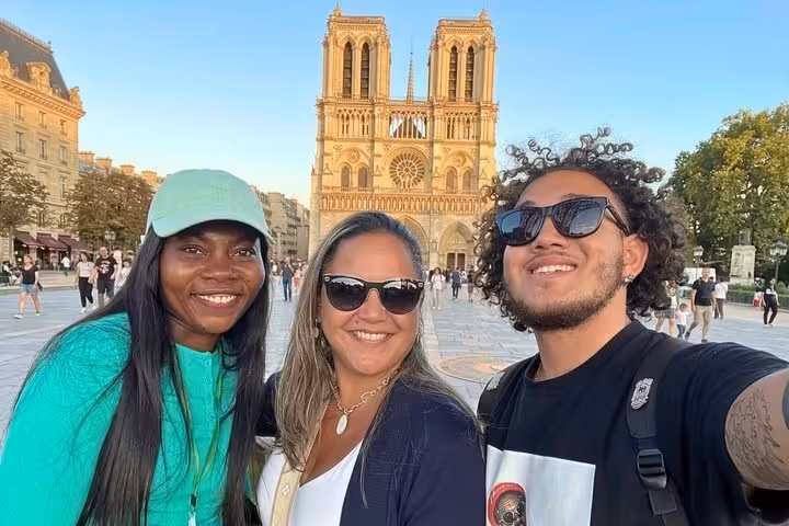 Happy tourists taking selfie in front of Notre Dame Cathedral Paris during a guided Gothic architecture walking tour