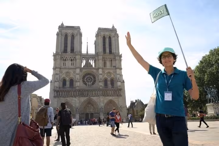 Tour host waving flag in front of Notre Dame Cathedral Paris showcasing iconic Gothic facade and rose window