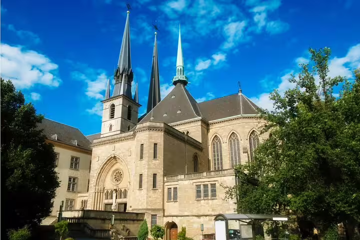 Notre-Dame Cathedral in Luxembourg City with Gothic spires and stone facade surrounded by green trees