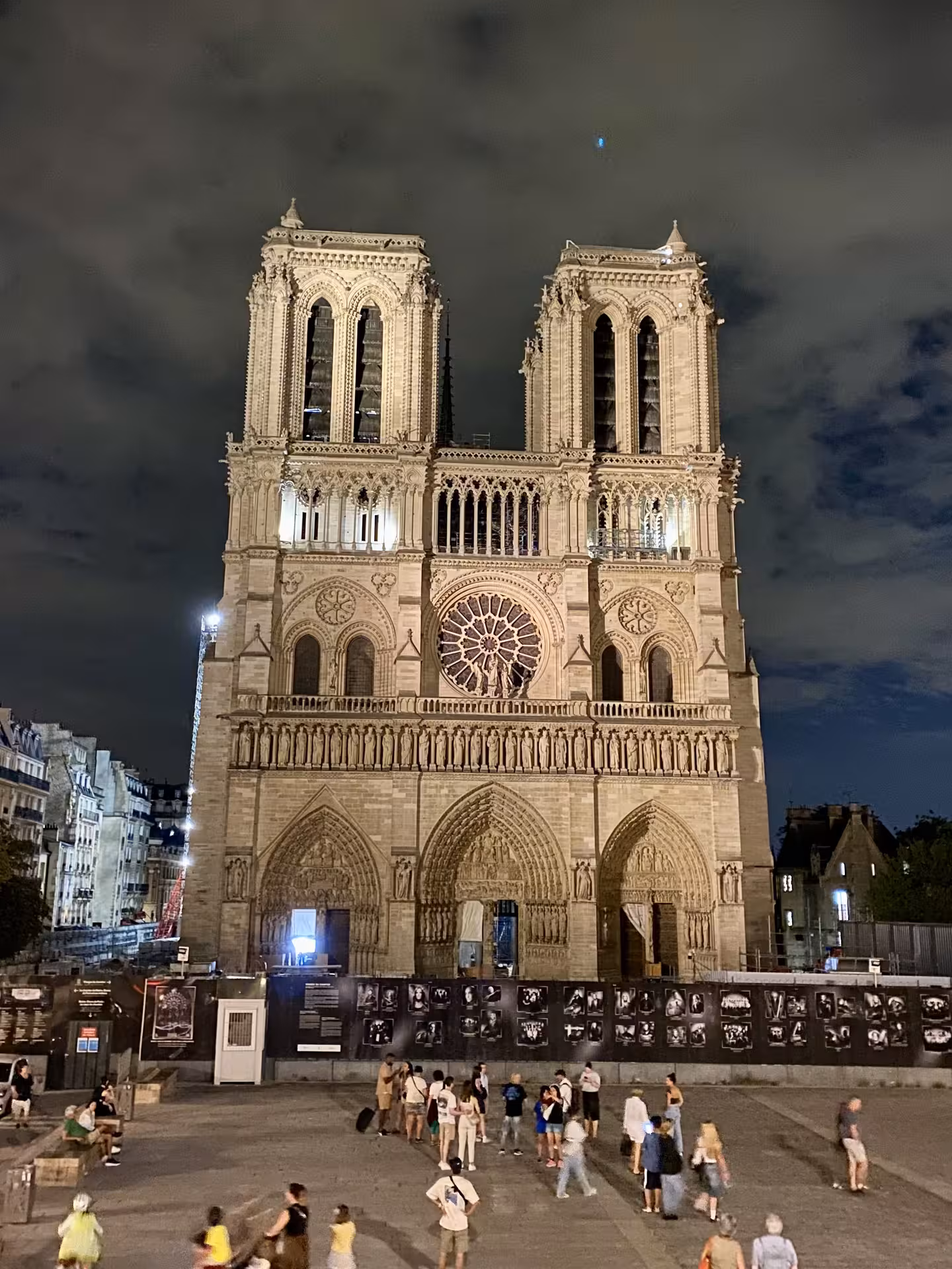 Night view of Notre-Dame Cathedral, an iconic stop on the Paris French Revolution Tour, with visitors exploring.