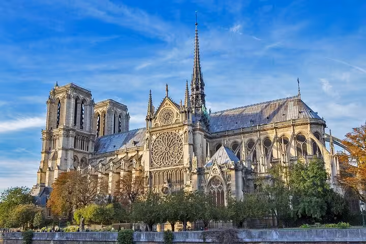 Notre Dame Cathedral Gothic facade with spire and rose window viewed from the Seine River in Paris