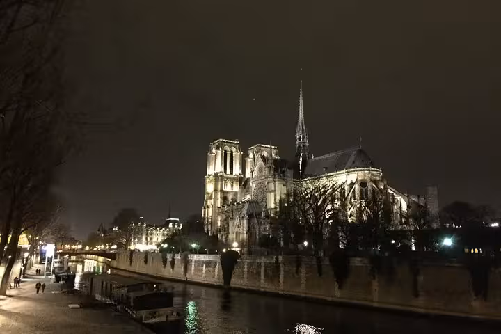 Notre-Dame Cathedral illuminated at night beside the Seine River in Paris