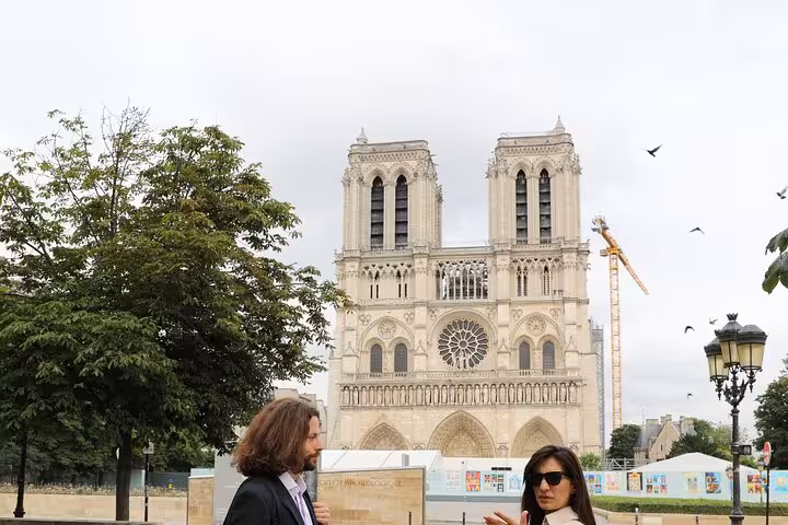 Notre-Dame Cathedral front with visitors and restoration crane, featured on a private historical tour in Paris