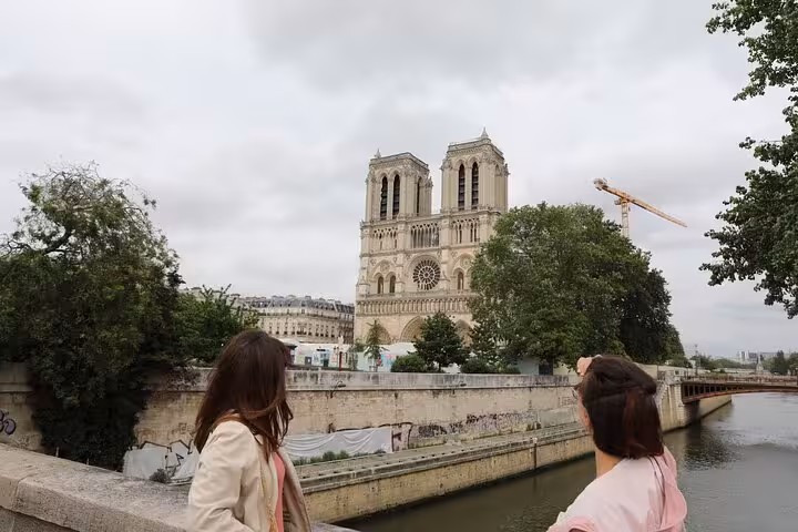 Travelers view Notre-Dame Cathedral from the Seine River bank, a highlight of a private historical tour