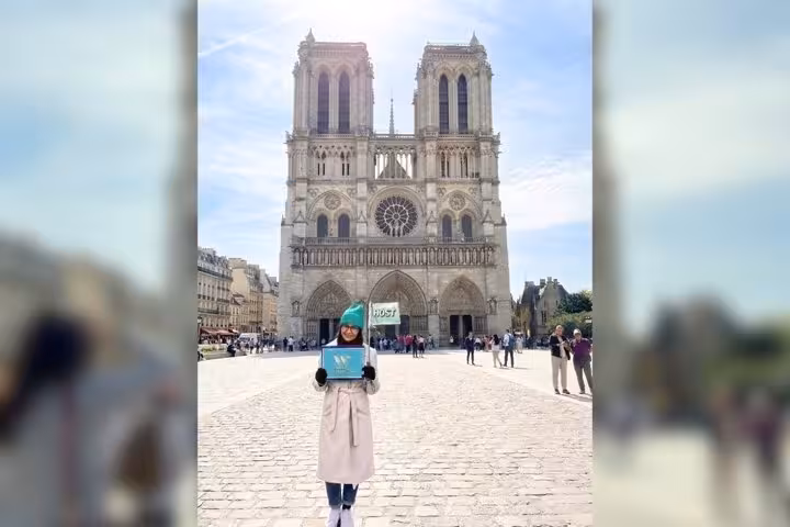 Tour guide holding sign in front of Notre Dame Cathedral Paris Gothic architecture facade on walking tour