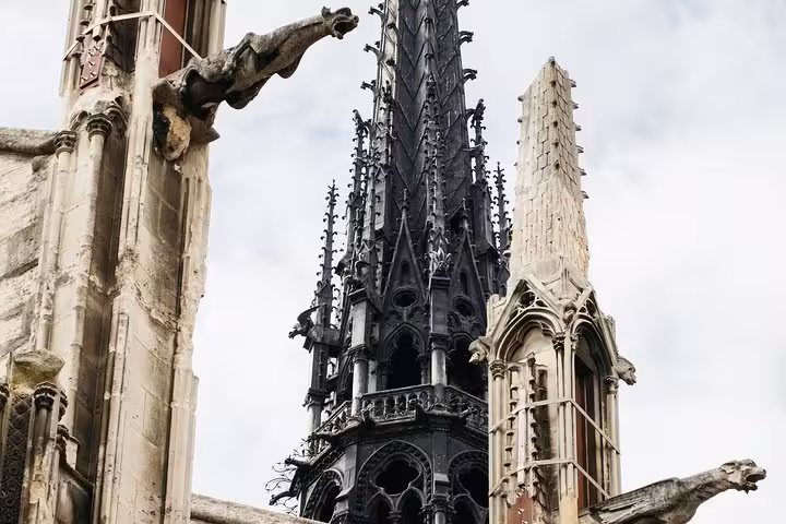 Close-up of Notre-Dame spire and stone gargoyles on exterior, featured on 90-minute semi-private tour in Paris