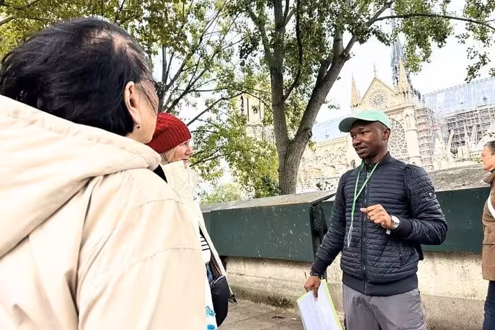 Expert guide explaining Notre Dame Cathedral Gothic architecture to tourists during a Paris walking tour