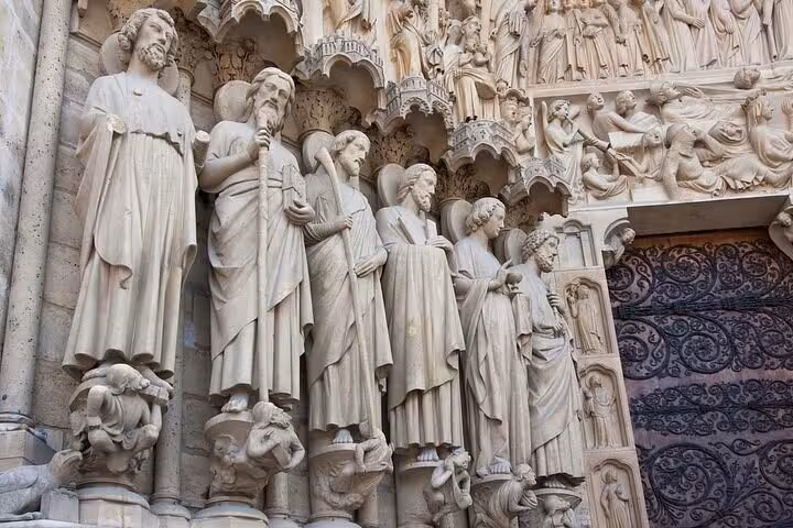 Intricate Gothic stone sculptures of saints adorn Notre Dame Cathedral Paris facade on a walking tour