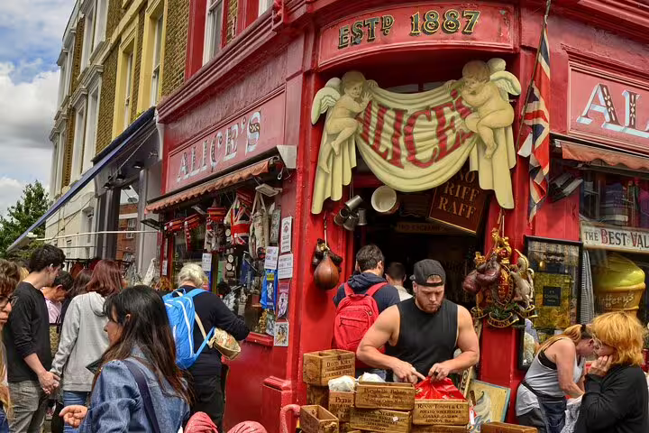 Bustling Notting Hill market scene with vibrant shoppers outside Alice's Antiques, a highlight on a London private tour.