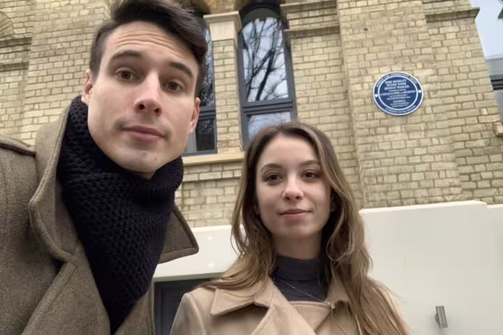 Couple taking selfie outside historic Notting Hill building with blue heritage plaque