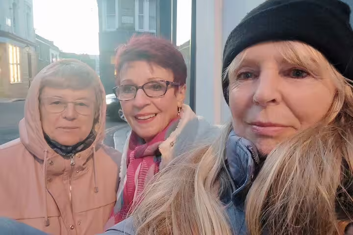 Three women smiling together on a Notting Hill street during a walking tour