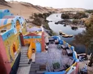 Colorful Nubian village buildings overlooking the Nile River with boats in Aswan, Egypt