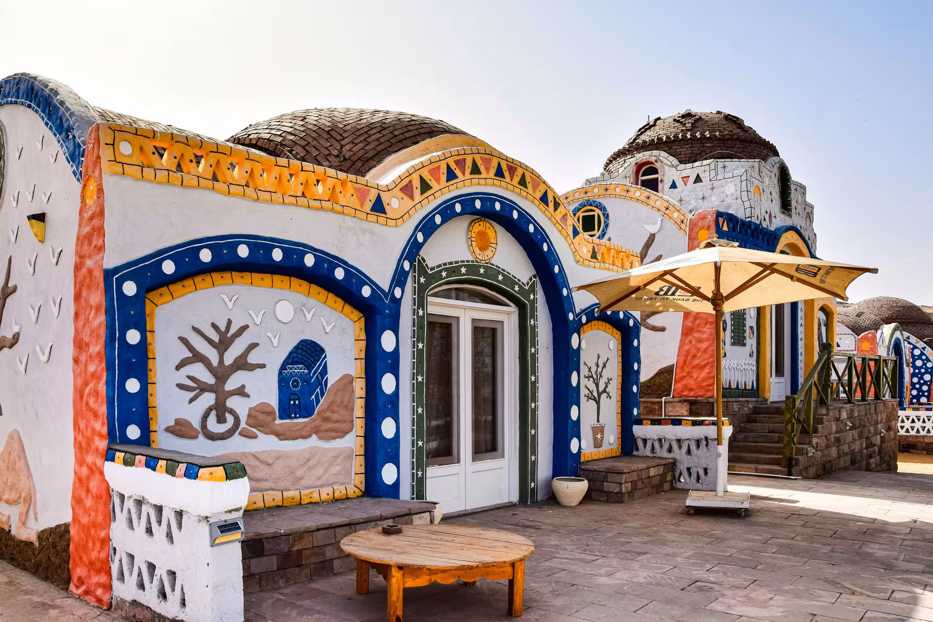 Colorful Nubian village building with dome roofs, mosaic arches, and traditional painted murals in Aswan, Egypt