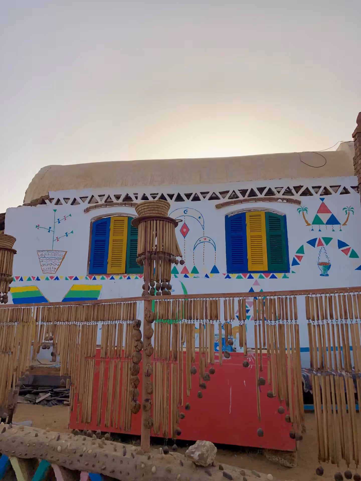 Colorful Nubian village house with painted murals, blue and yellow shutters, and traditional reed decorations in Aswan
