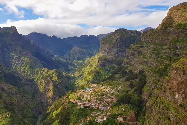 Aerial view of Nun's Valley village nestled in lush green mountains under a partly cloudy sky.