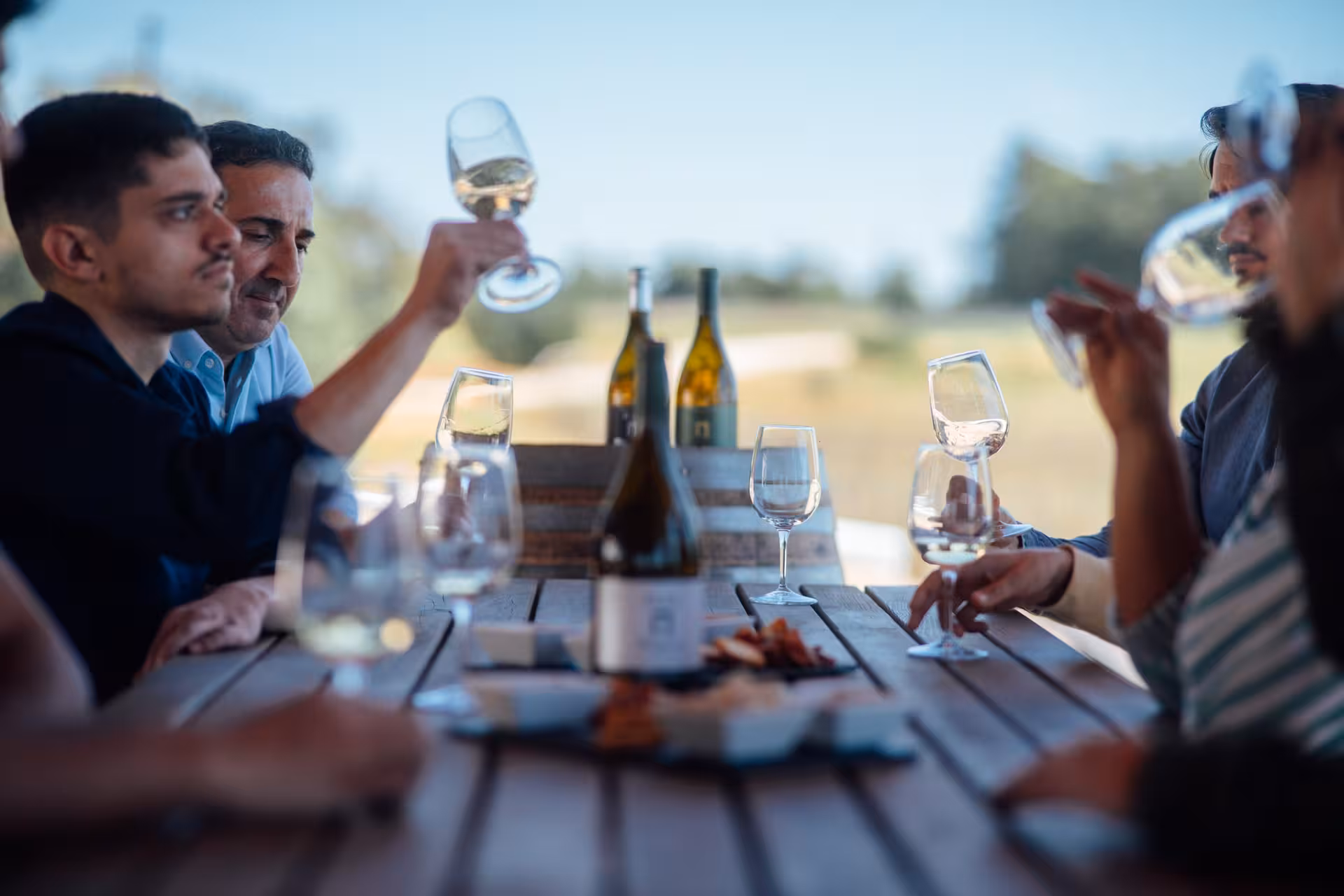 Guests toasting white wine at an outdoor table on the Núr Paxá Visit & Superior Test vineyard tasting tour