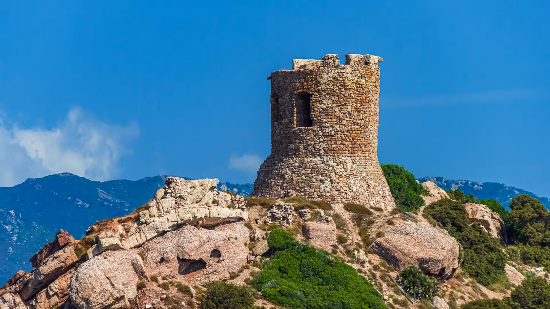 Close-up of a historic tower atop rocky hills in Porto Conte Park, a highlight of the Alghero minivan tour.