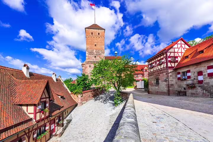 Medieval Nuremberg Castle tower with half-timbered buildings and cobblestone path on a sunny day