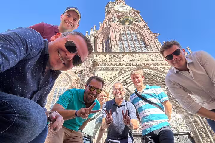 Friends pose by Nuremberg Frauenkirche on a city scavenger hunt and sights self-guided walking tour in Germany