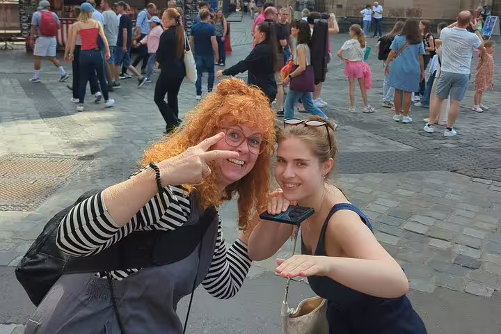 Two women smiling and posing with a phone game in a medieval Nuremberg town square