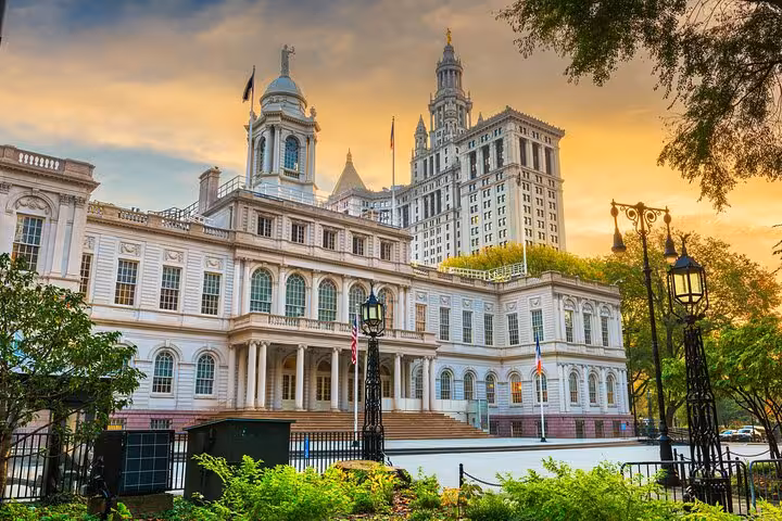 New York City Hall building in Lower Manhattan with ornate white facade and lamp posts at sunset