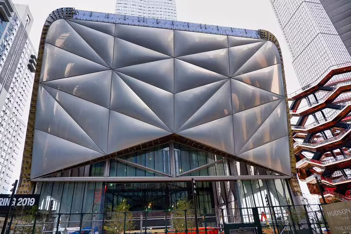 The Shed building with geometric metallic facade next to the Vessel sculpture at Hudson Yards NYC