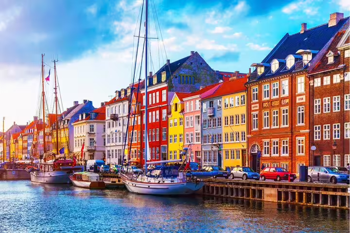 Colorful historic buildings lining Nyhavn canal with sailboats docked in Copenhagen, Denmark