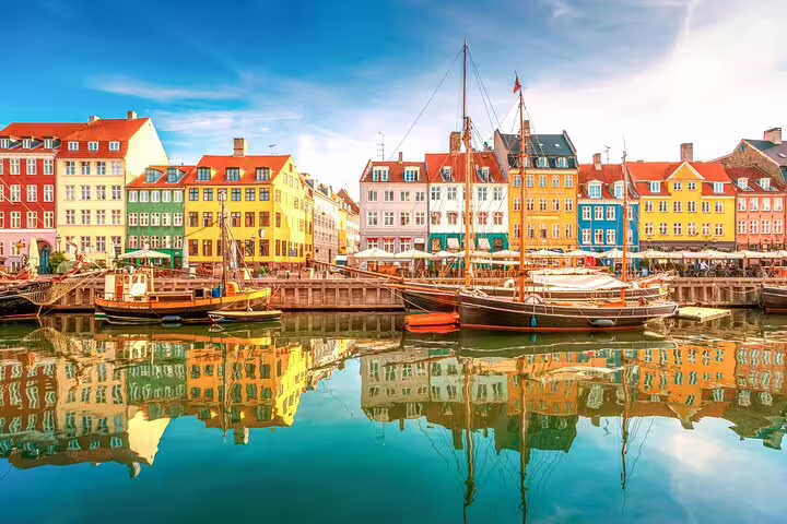 Colorful historic buildings reflecting in Nyhavn canal with sailboats, Copenhagen Denmark