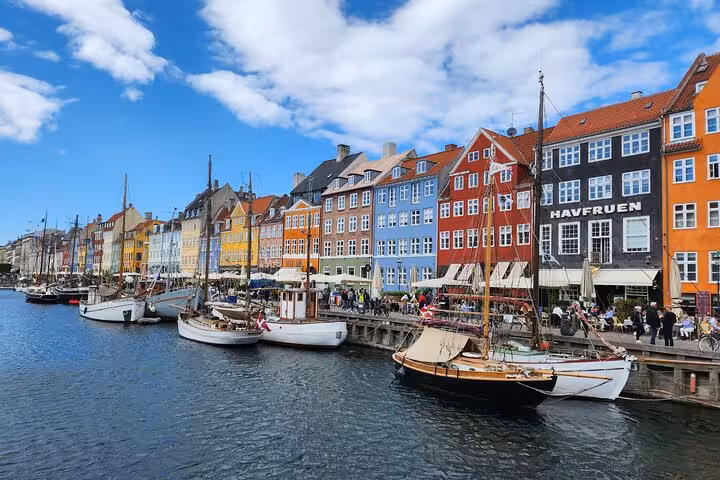 Nyhavn, Copenhagen's iconic waterfront with vibrant buildings and docked boats on a sunny day.