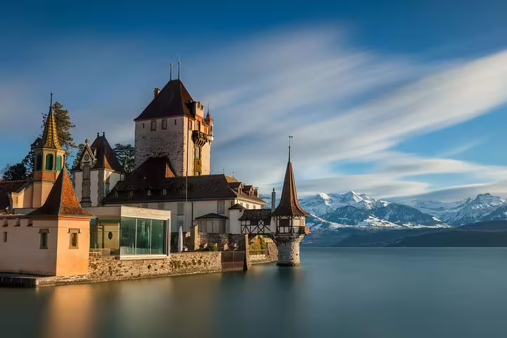 Medieval Oberhofen Castle on Lake Thun with snow-capped Swiss Alps in background