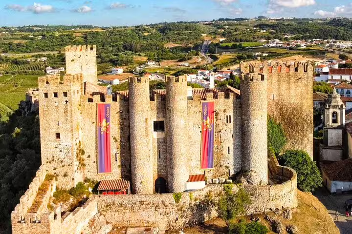 Aerial view of Óbidos Castle surrounded by lush landscape, featured in a small group day tour from Lisbon to Fátima, Nazaré, and Óbidos.