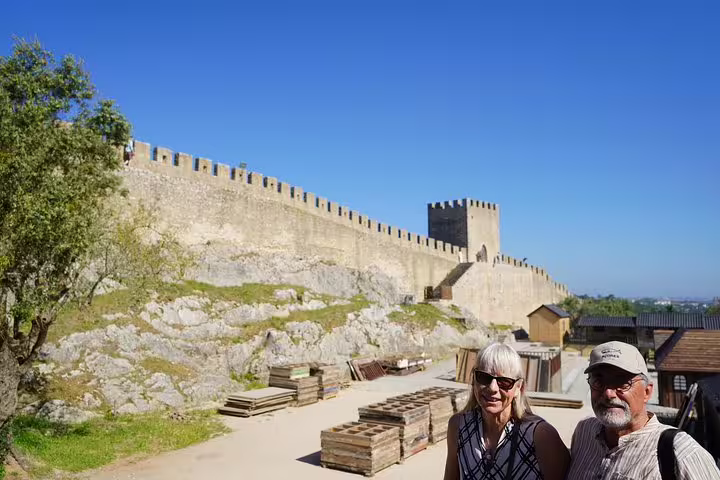 Tourists enjoying the historic Óbidos Castle under a clear blue sky on a full-day private tour from Lisbon, Portugal.