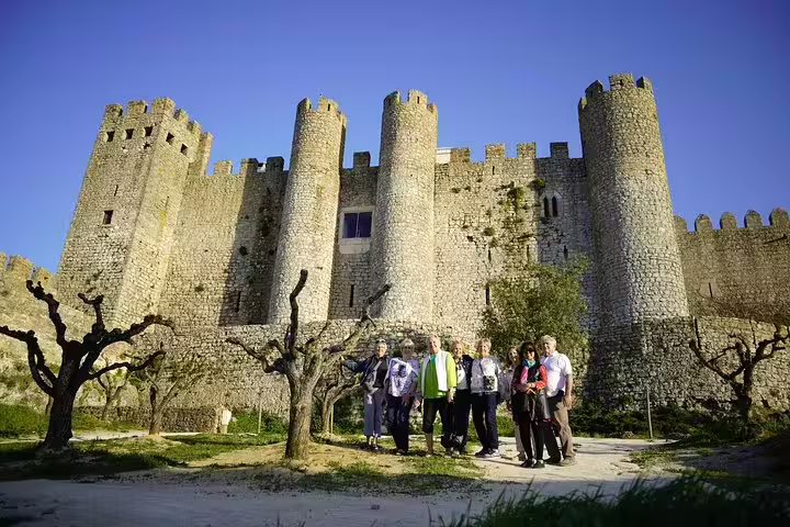 Tourists explore the medieval Óbidos Castle during a full-day private tour from Lisbon, including Nazaré and Fátima.