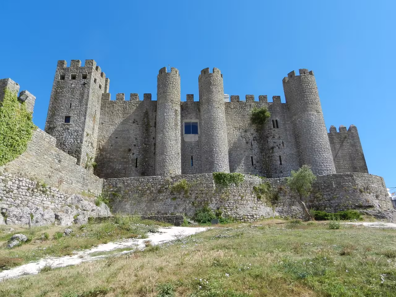 Explore the majestic medieval Óbidos Castle under a clear blue sky on our Fairytale Escapes tour in Portugal.