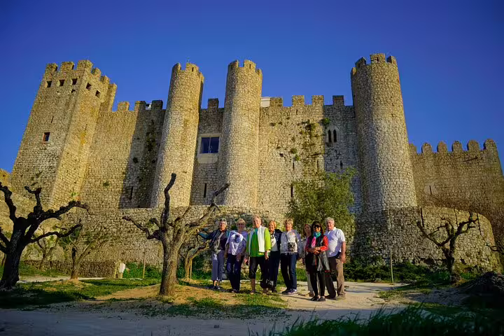 Group of tourists exploring the historic Óbidos Castle, a UNESCO World Heritage site near Lisbon, on a sunny day tour.