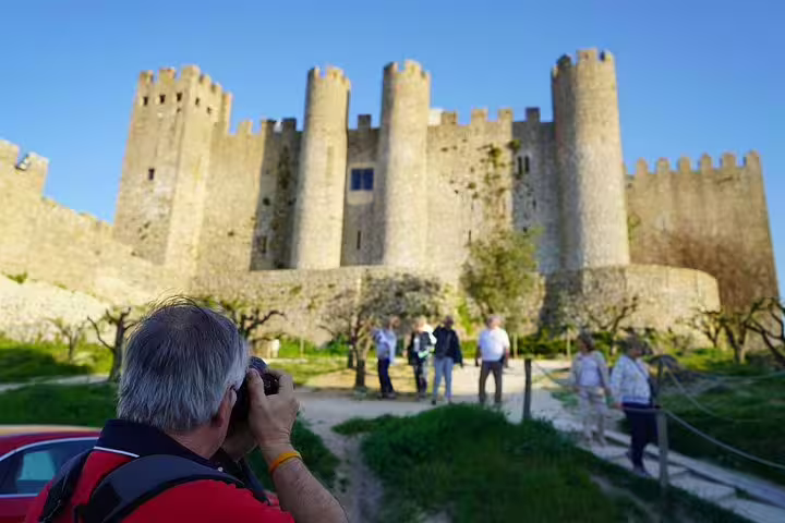 Tourist captures the stunning medieval castle of Óbidos, Portugal, highlighting its historical charm on the Vicentine Coast tour.