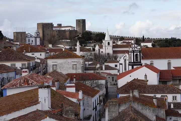 Scenic view of Óbidos' medieval architecture with castle and church, perfect for a private day tour to Óbidos, Nazaré, and Alcobaça.
