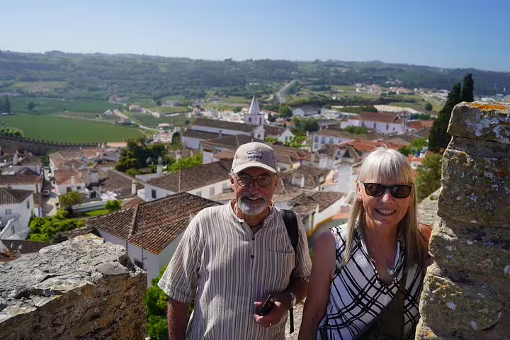 Tourists enjoying scenic views of Óbidos from Lisbon on a full-day private tour, with historic architecture and lush landscapes in the background.