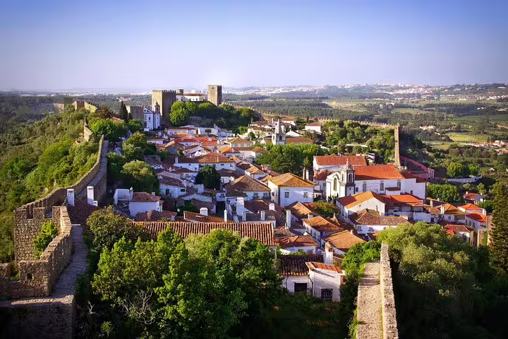 Aerial view of the historic town of Óbidos, Portugal, showcasing medieval walls and charming rooftops on a sunny day.