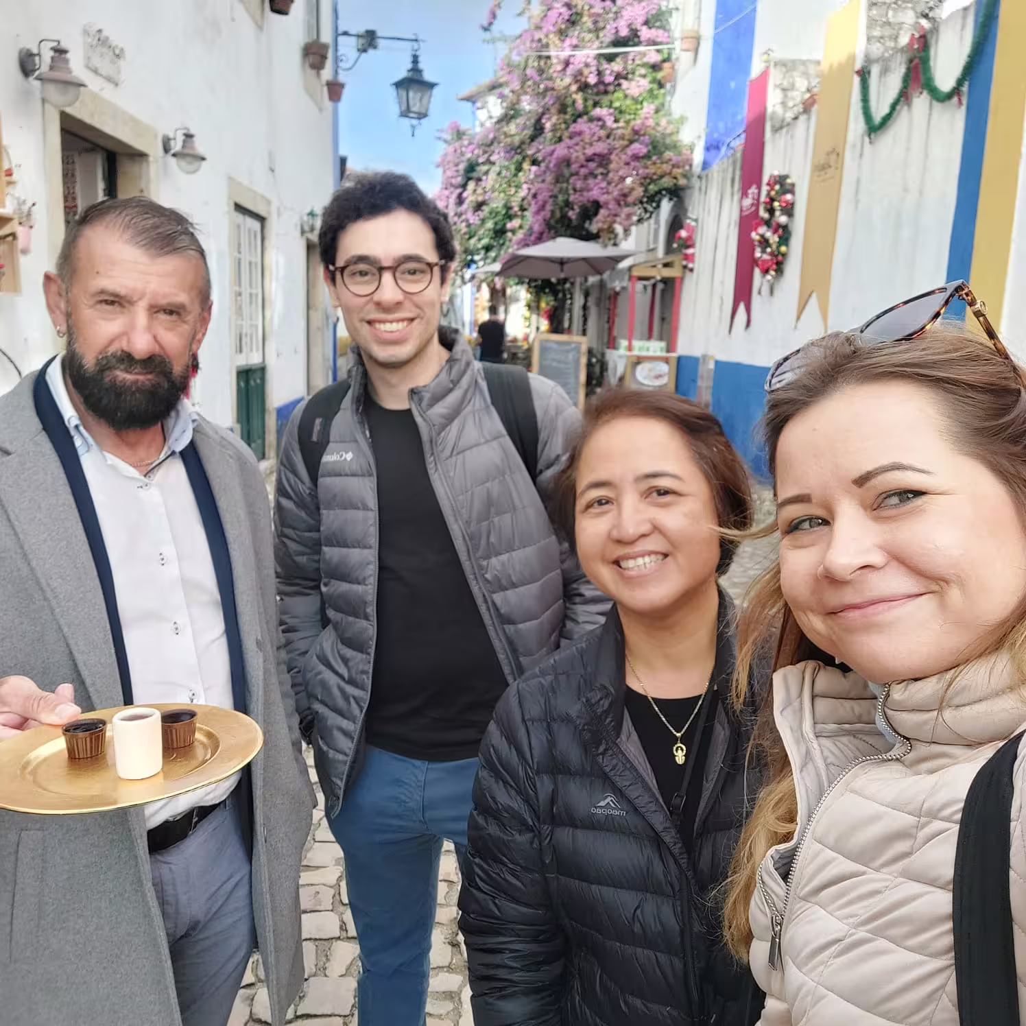 Happy tourists enjoying drinks on a charming street in Óbidos during the Lisbon guided tour.