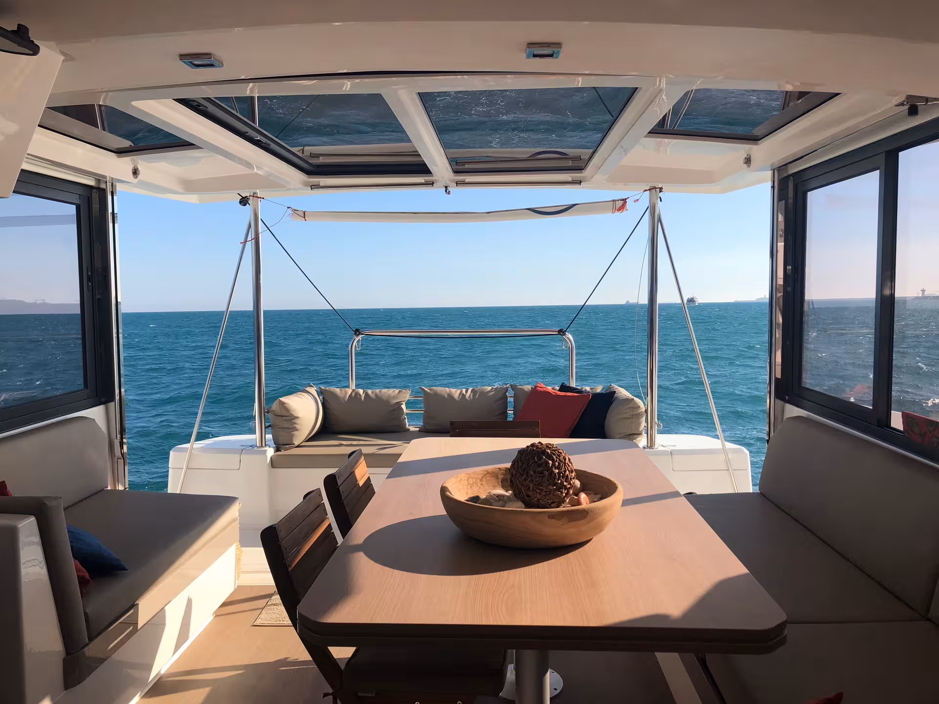Ocean-view catamaran table for dining with a private chef, sunset light, cozy lounge and open deck