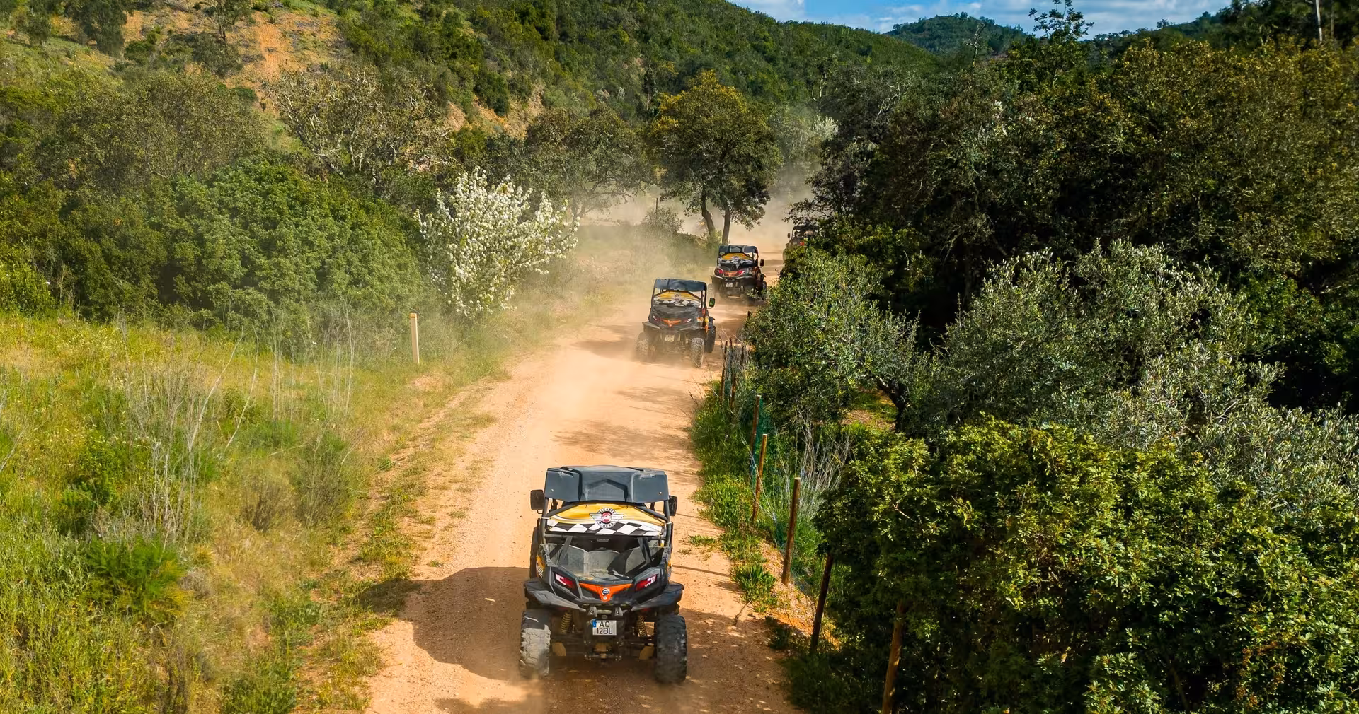 Off-road buggy tour speeding along a dusty countryside track through lush Algarve hills and green valleys
