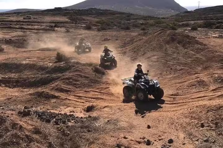 Riders blaze dusty trails on quad bikes, emphasizing the excitement of off-road adventure tours.