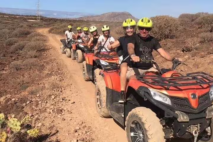 Group of riders navigate challenging dirt paths on quad bikes, highlighting adventurous off-road experience.