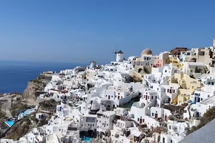 Panoramic Oia village with windmills and white cave houses above the caldera, Santorini cruise excursion
