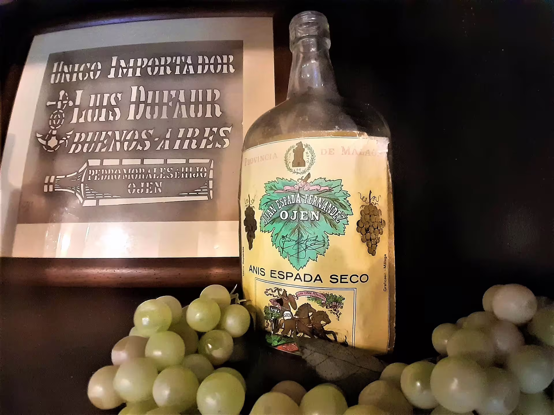 Vintage Ojen anise liqueur bottle with grapes and old label display, featured tasting on Ojen private tour from Costa del Sol