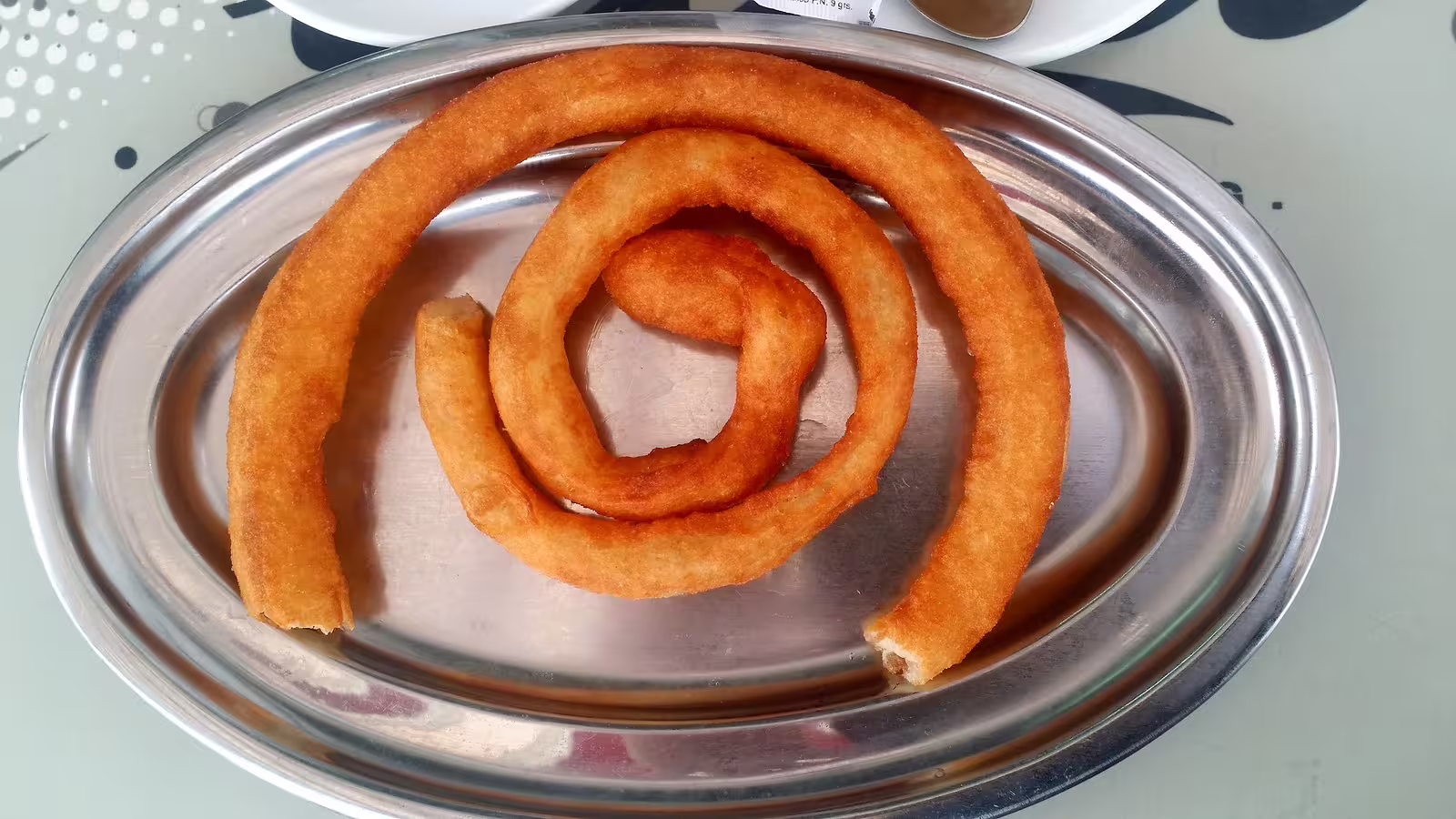 Traditional Andalusian churros spiral served on a metal platter, a tasty stop on an Ojen private tour from Costa del Sol