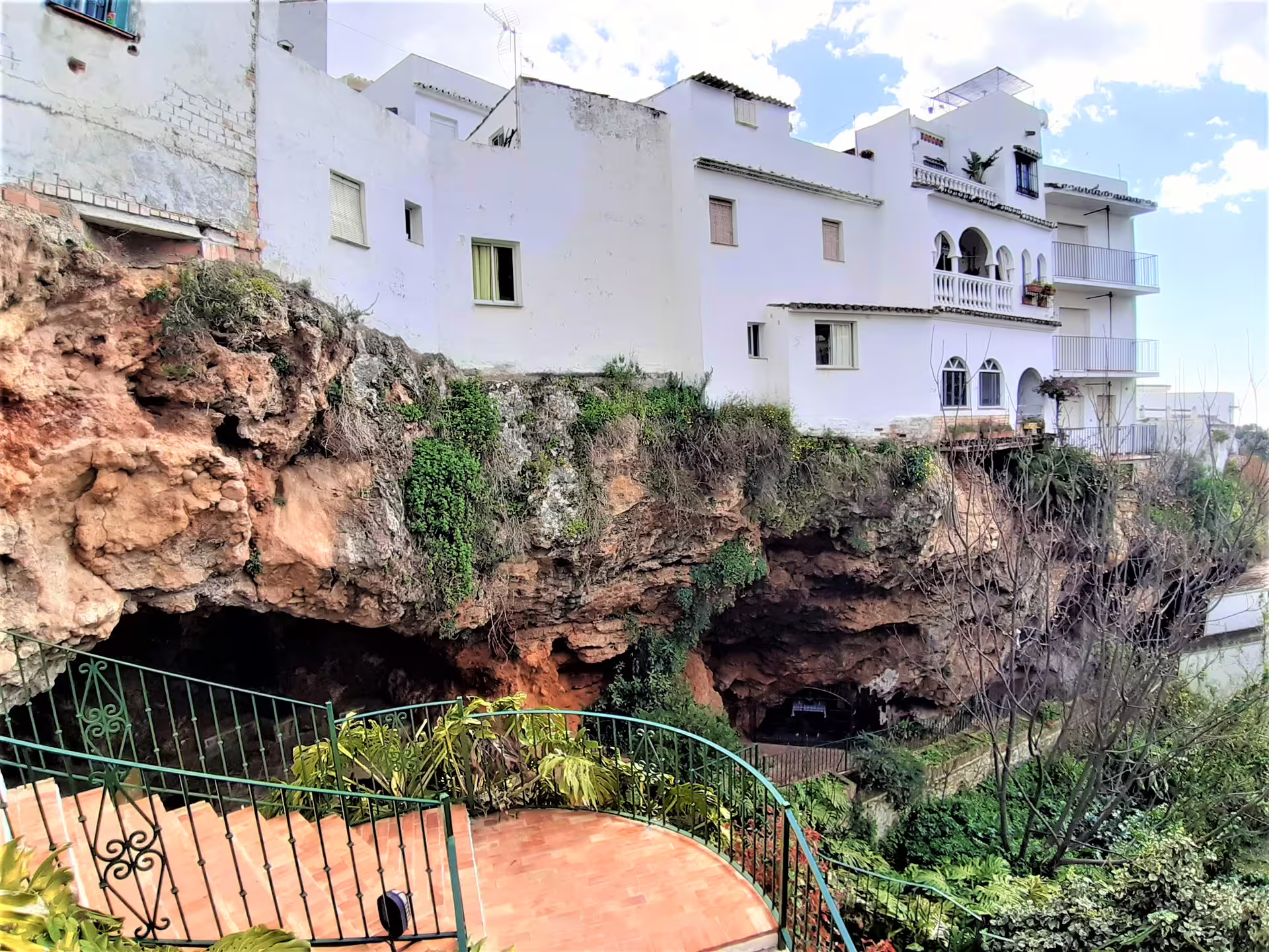 White houses perched above a rocky cave in Ojén, Andalusia, featured on a private walking tour route