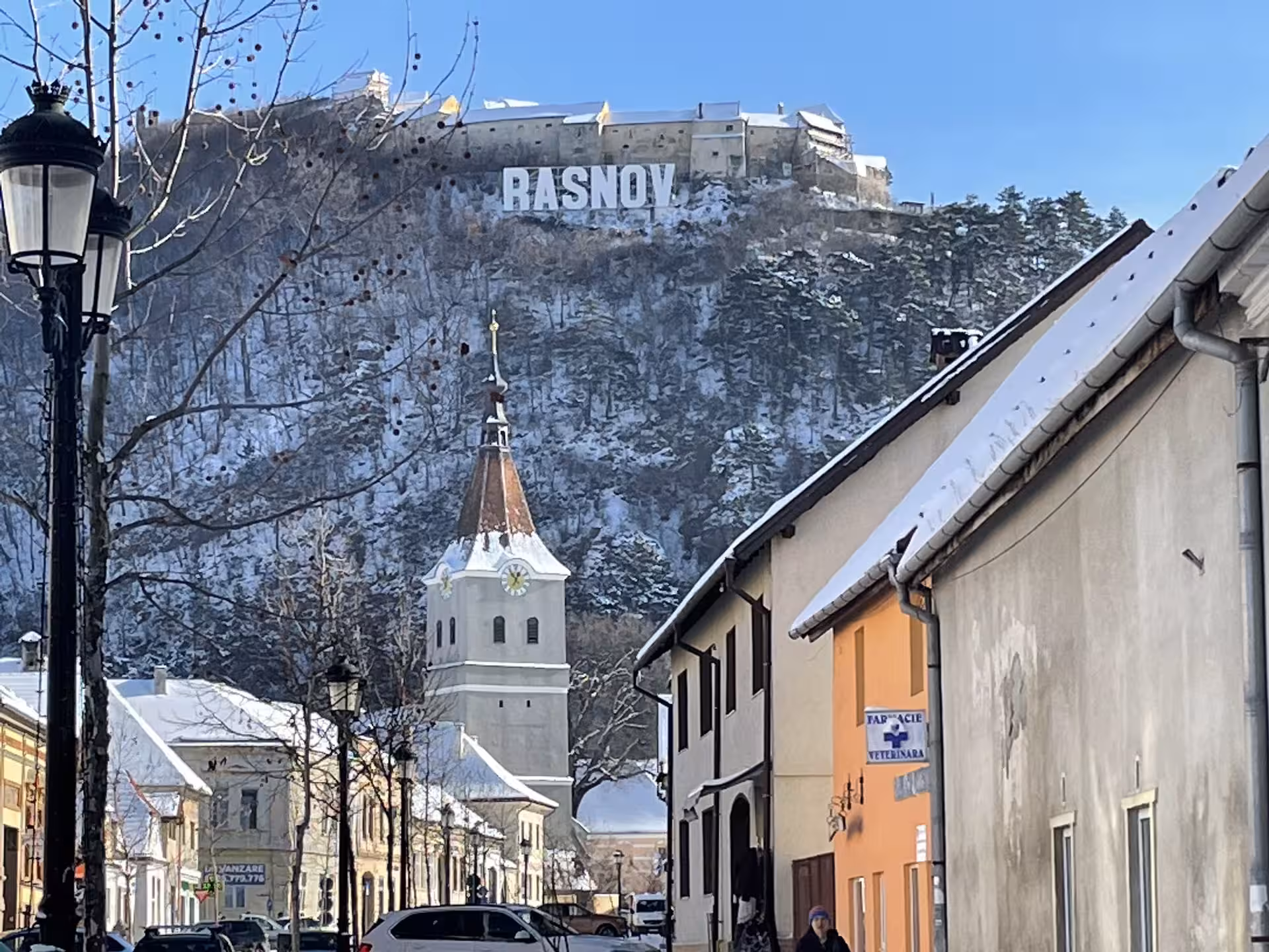 Rasnov town center with snow-covered fortress hill and church tower in winter, Romania