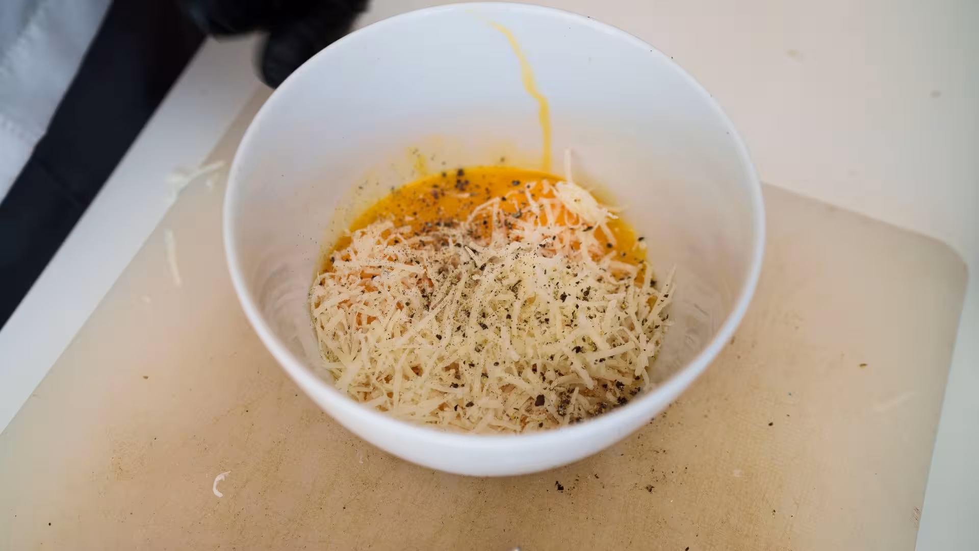 Preparing carbonara sauce with fresh eggs and grated cheese in Olbia cooking class.